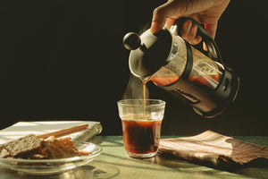 A french press pouring coffee into a cup